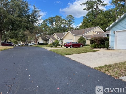 A residential street with houses on both sides and a car parked on the driveway.