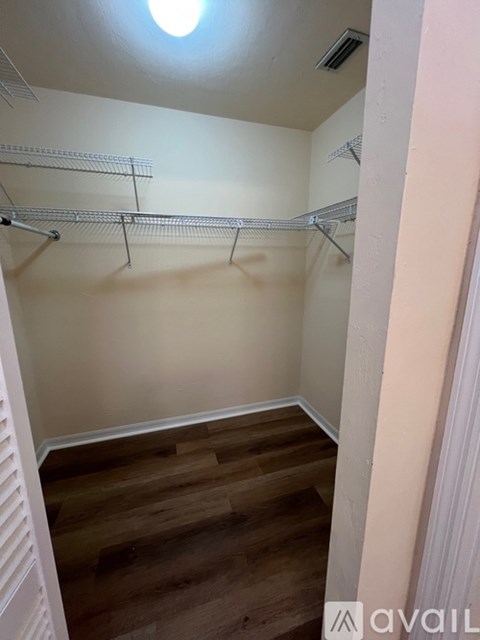 A small, empty room with a wooden floor and metal shelving.