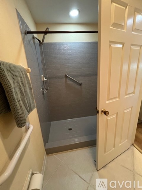 A bathroom with a walk-in shower and a towel hanging on the tub.