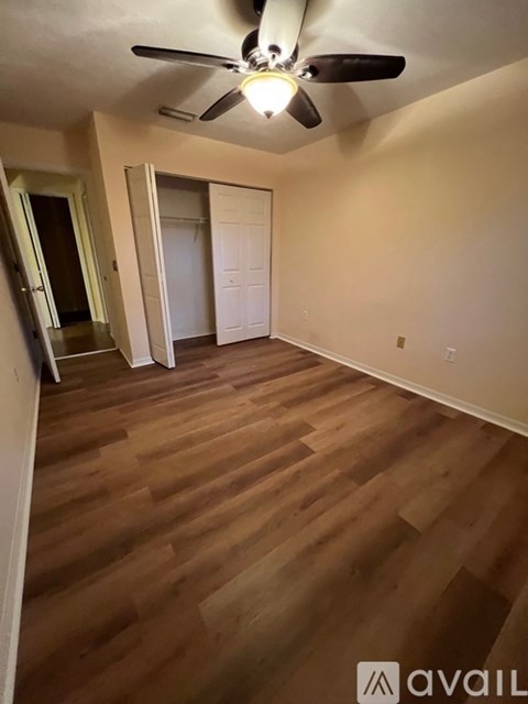 A room with a ceiling fan and wooden flooring.