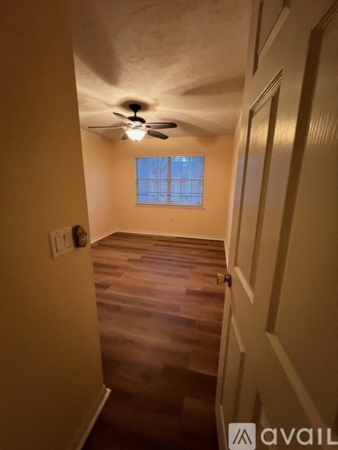 A room with a ceiling fan and a window with blinds.