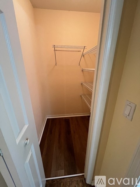 A white door opens to a small pantry with a shelf and a light switch.