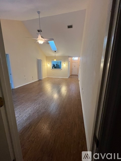 A long hallway with a fan and light on the ceiling.