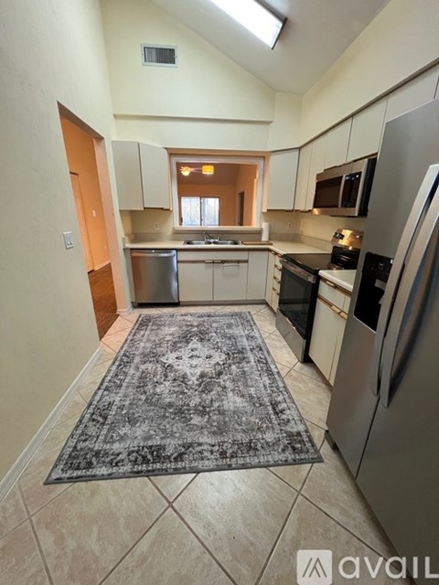 A kitchen with a rug on the floor and a refrigerator on the right.