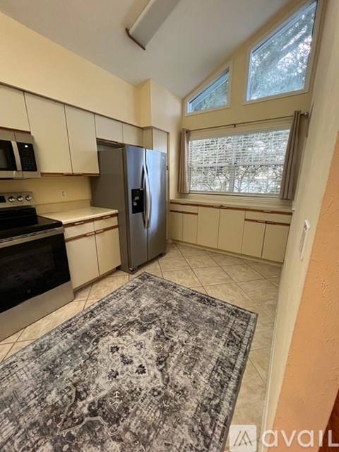 A kitchen with a rug on the floor and a refrigerator.