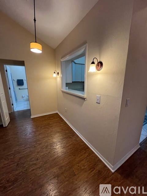 A room with wooden floors and a window with a mirror above it.