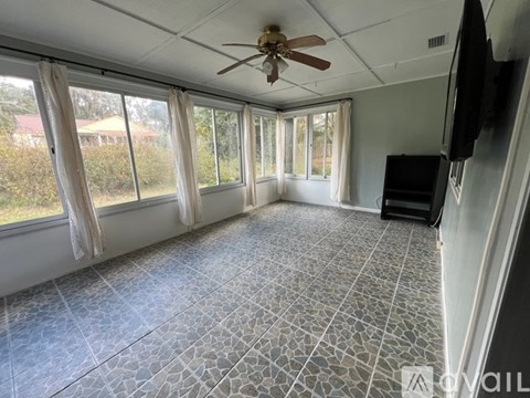 A spacious room with a ceiling fan and a flat screen TV mounted on the wall.