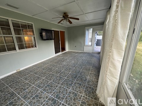 A room with a ceiling fan and a television mounted on the wall.