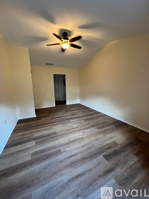 A room with a ceiling fan and wooden flooring.