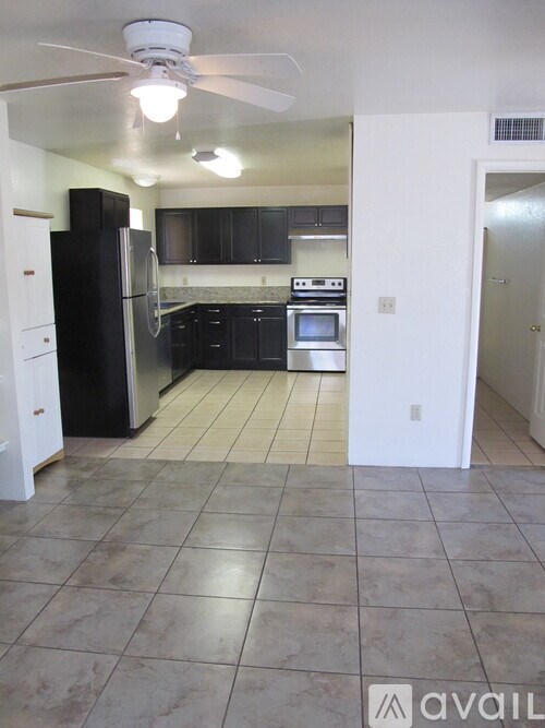 A kitchen with black cabinets and a white refrigerator.