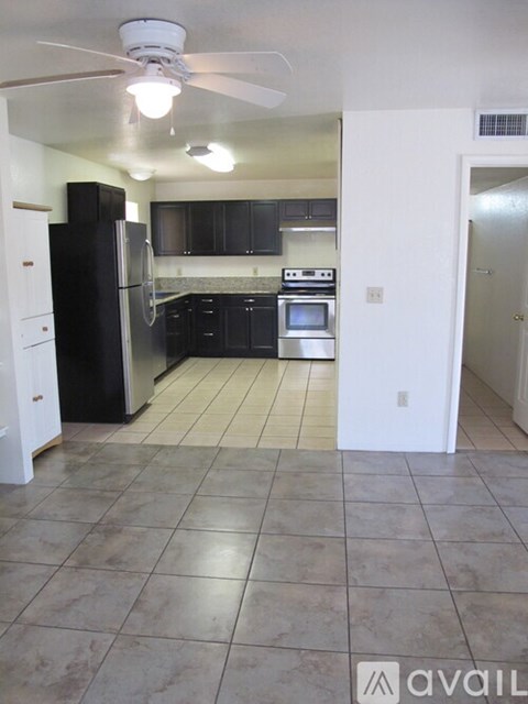 A kitchen with black cabinets and a white refrigerator.