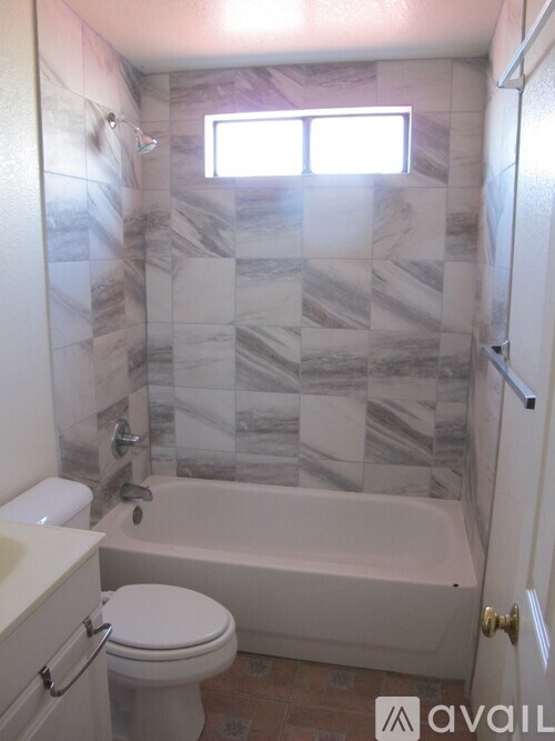 A bathroom with a marble tile wall and a white bathtub.