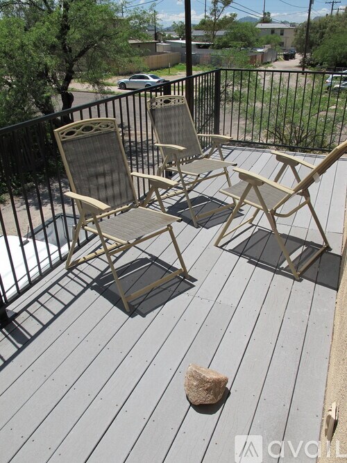 Two chairs are on a deck with a rock in front of them.