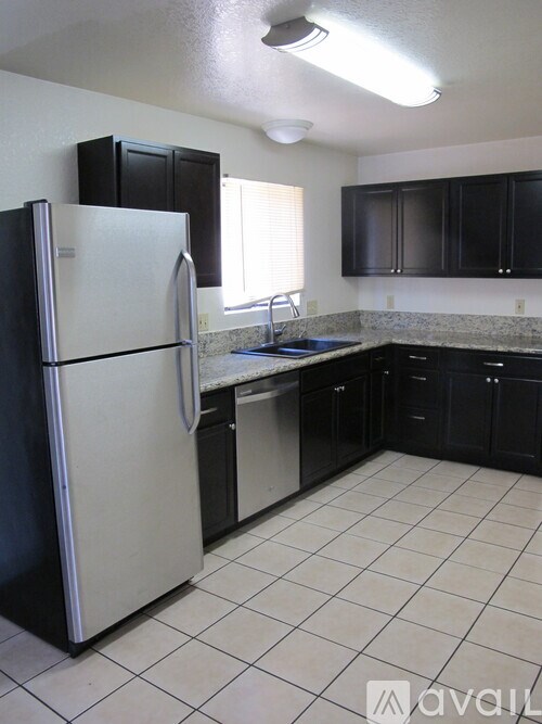 A kitchen with a white refrigerator and black cabinets.