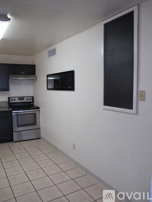 A kitchen with black cabinets and a stainless steel oven.