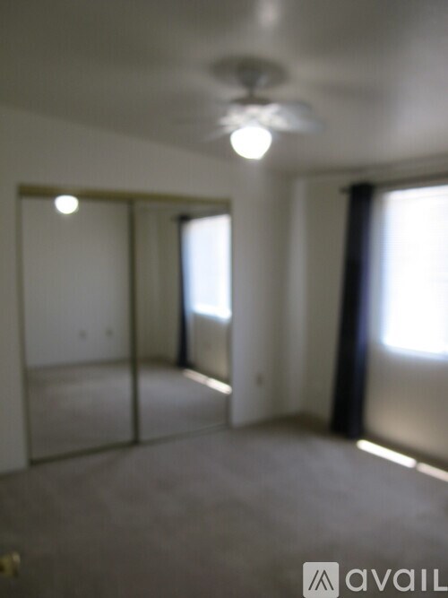 A room with a ceiling fan and sliding glass doors.