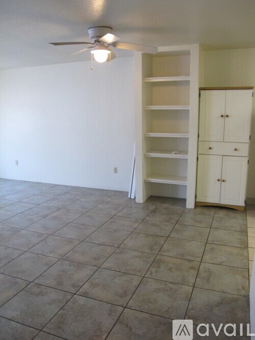 A room with a ceiling fan and a cabinet.
