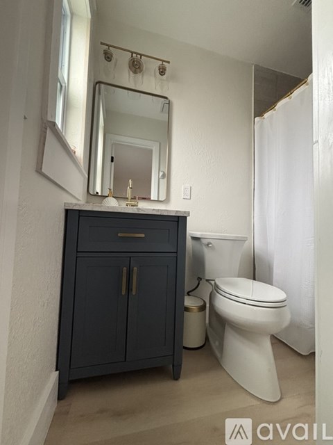 A bathroom with a toilet, sink, and mirror.