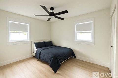 A bedroom with a bed, two windows, and a ceiling fan.