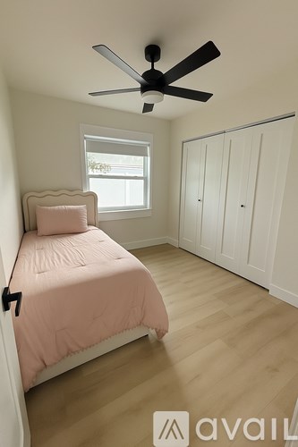 A bedroom with a bed, a window, and a ceiling fan.