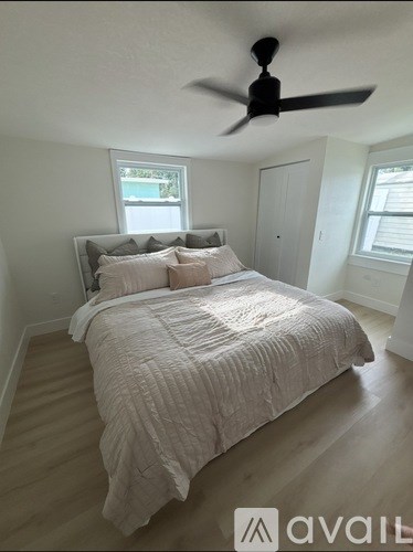 A bedroom with a bed, a ceiling fan, and a window.