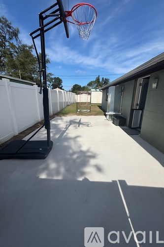 A basketball hoop is mounted on a stand in a backyard.
