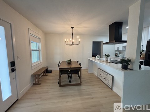 A modern kitchen with a dining table and chairs in the center.