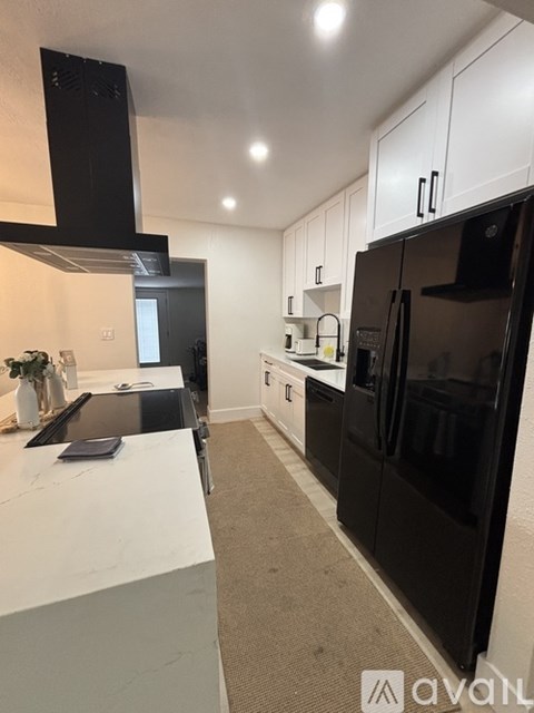 A modern kitchen with black appliances and white cabinets.