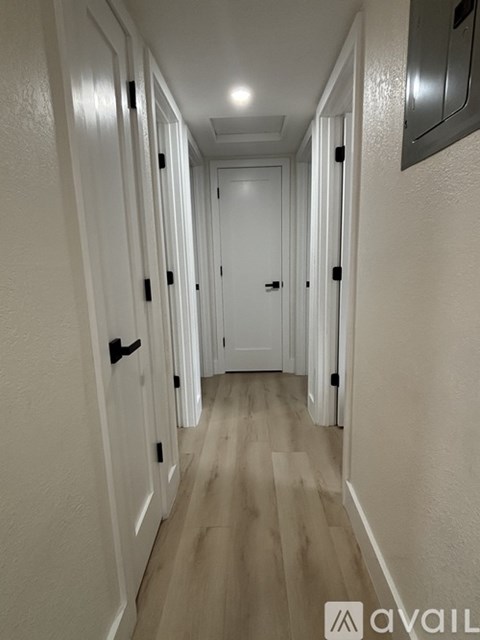 A long hallway with white doors and wooden floors.