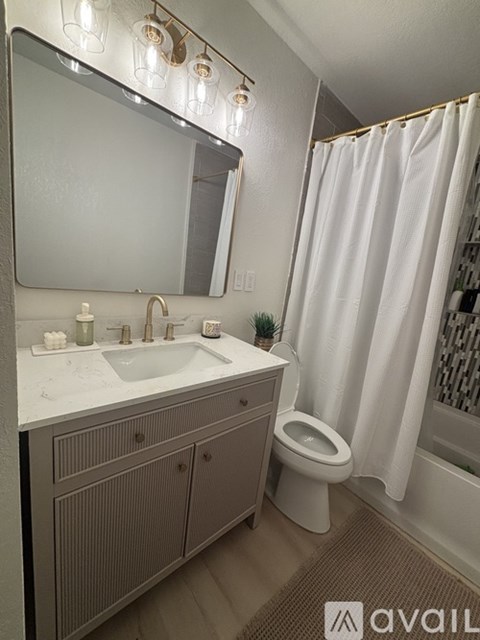 A bathroom with a sink, toilet, and a mirror.