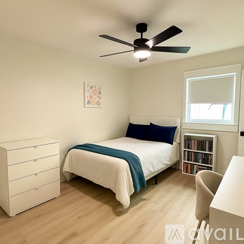 A bedroom with a bed, a dresser, a chair, and a ceiling fan.