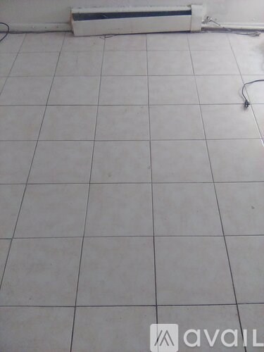 A room with white tiled flooring and a white wall.