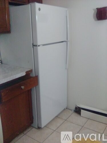 A white refrigerator in a kitchen with wooden cabinets.