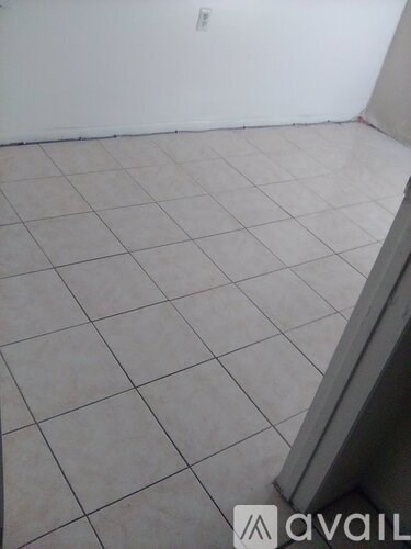 A room with white tiled flooring and a white wall.