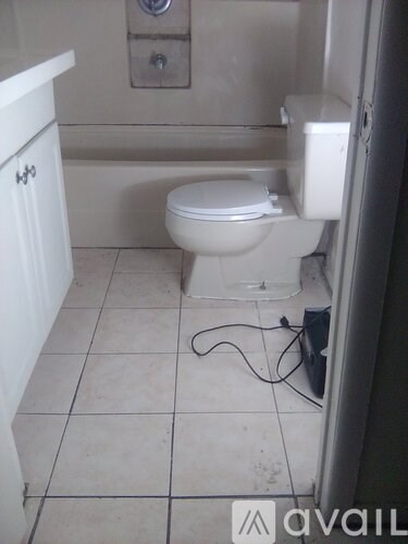A white toilet in a bathroom with a white cabinet and a white wall.