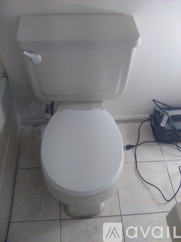 A white toilet with a cord on the floor.