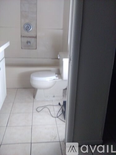 A white toilet in a bathroom with a cord on the floor.