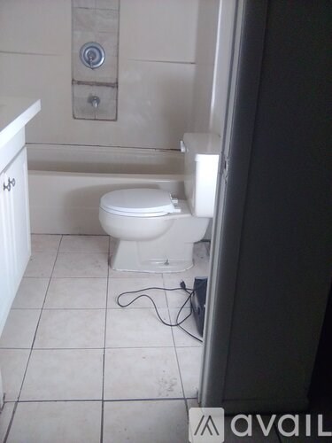 A white toilet in a bathroom with a cord on the floor.