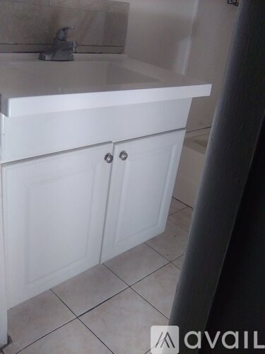 A white cabinet with two doors is in a bathroom.
