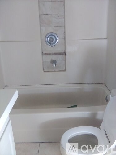 A white toilet is next to a bathtub in a bathroom.