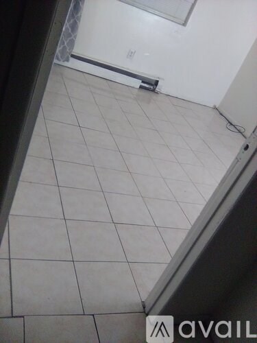 A room with white tiled flooring and a doorway leading to another room.