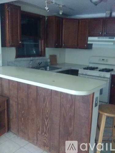 A kitchen with wooden cabinets and a white stove top oven.