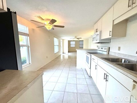 A kitchen with white cabinets and a black refrigerator.