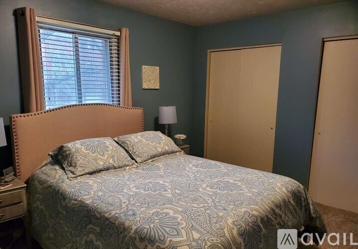 A bedroom with a bed, nightstand, and two doors.