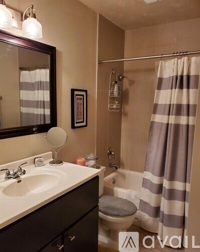 A bathroom with a sink, mirror, toilet, and striped shower curtain.