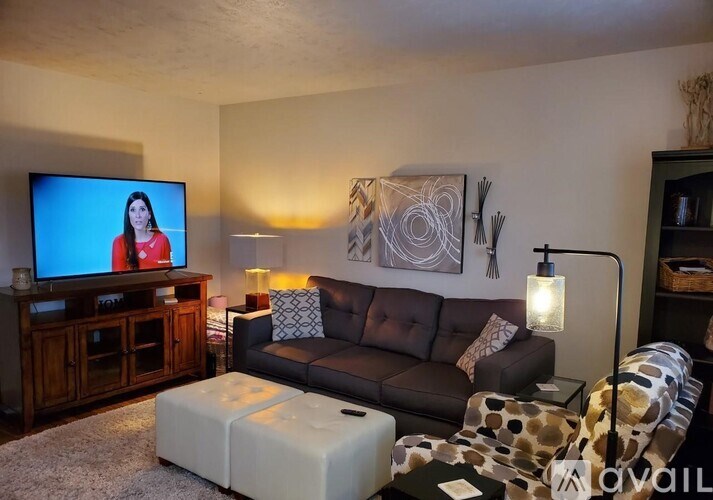 A living room with a leather couch, a television, and a coffee table.