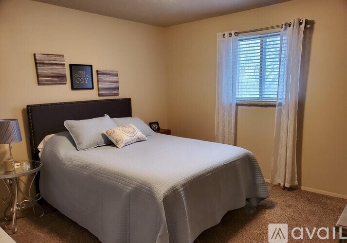 A bedroom with a bed, nightstand, and window.
