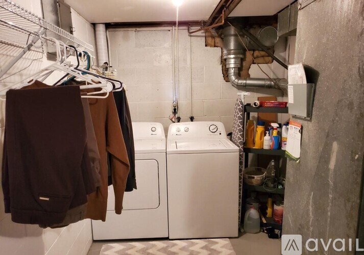 A laundry room with a washer and dryer, a shelf with cleaning supplies, and clothes hanging up.