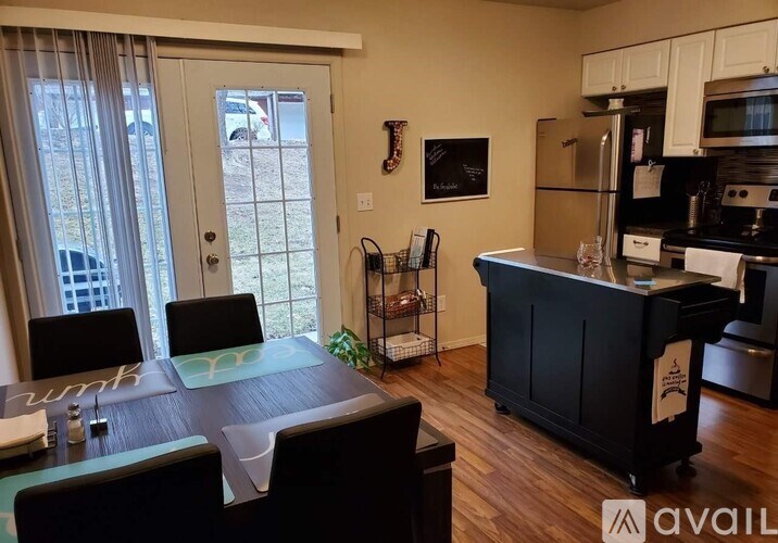 A kitchen with a black island and white cabinets.