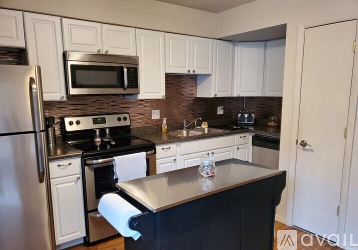 A kitchen with white cabinets and a black countertop.